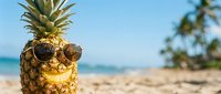 Cool pineapple with sunglasses on tropical beach with palm trees and ocean background for summer vacation and holiday concepts.