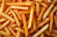Crispy golden french fries in close-up view showing texture and detail of fried potato strips. Fresh hot fast food background for restaurant menu and food service.