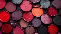 Colorful lipstick collection in round containers showing various shades from red to purple and pink tones for beauty and cosmetics industry.