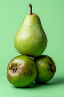 Fresh green pear balanced on two round pears against vibrant mint background, creating playful composition for food marketing and healthy lifestyle content.