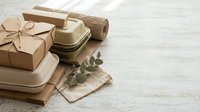 Eco-friendly gift wrapping with kraft paper boxes, natural twine, eucalyptus leaves and handmade soap on rustic wooden background for sustainable packaging.