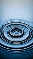 Water ripples creating concentric circles on calm blue surface with gradient background for meditation wellness and tranquility concepts.