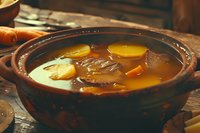 Traditional clay pot filled with hot steaming broth, carrots and mushrooms in golden savory soup, rustic wooden table setting creates cozy atmosphere.