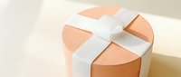 Elegant round gift box with white ribbon bow on neutral background for special occasions and celebrations.