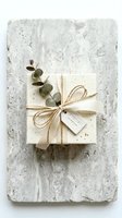 Elegant gift box wrapped in cream paper with twine bow, ribbon, eucalyptus sprig, and special offer tag on marble surface.