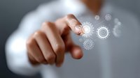Businessman pointing at glowing digital gears and cogs interface, demonstrating business process automation and technological innovation concept.