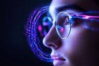 Young Asian woman in glasses illuminated by vibrant neon circles and digital light effects against dark background, showcasing futuristic technology concept.