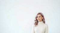 Young woman with long wavy lavender-toned hair wearing a cream turtleneck sweater against a white background, suitable for portrait and lifestyle design projects.