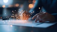 Hand typing on laptop keyboard in dark room with magical glowing particles and bokeh lights creating atmospheric digital transformation concept.