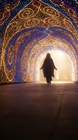 Silhouette of person walking through illuminated tunnel with golden lights creating ornate patterns. Magical archway with decorative lighting for festive celebrations.