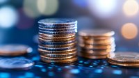 Stacked coins on illuminated computer keyboard with bokeh lights in background, representing digital finance and cryptocurrency investment trends.