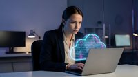 Professional businesswoman working on laptop with holographic cloud computing interface in modern office environment for technology and data management concepts.