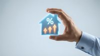 Hand protecting glowing house icon with percentage symbol and upward arrows representing mortgage rates, real estate investment growth concept.