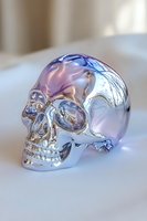 Iridescent metallic skull with holographic rainbow reflections on white surface, featuring detailed anatomical structure and smooth polished finish.