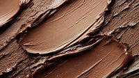 Chocolate brown makeup foundation cream with rich creamy texture showing brush strokes and swirls for cosmetic beauty and skincare applications.