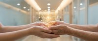 Young woman and mature man holding glowing golden light orb together in modern office, symbolizing teamwork, knowledge sharing, and business collaboration.