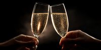 Two hands holding champagne flutes filled with sparkling wine against dark background, perfect for celebration, toast, anniversary, wedding, New Year.