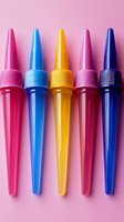 Colorful plastic icing piping bags arranged in row on pink background. Professional baking and cake decorating tools in vibrant pink, blue, yellow and purple.