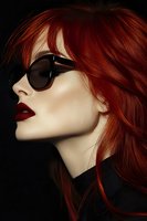 Stylish profile portrait of woman with vibrant red hair and sunglasses against dark background, wearing bold red lipstick and black turtleneck for fashion editorial.