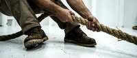 Strong hands gripping thick rope during intense workout training session. Fitness exercise concept for strength building and endurance sports activities.