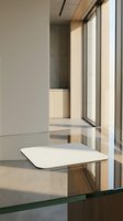 Modern minimalist office interior with white table and large windows showcasing natural light and contemporary architectural design elements.