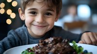Young boy enjoying chocolate dessert at restaurant with warm bokeh lights creating cozy dining atmosphere for family meal and celebration moments.