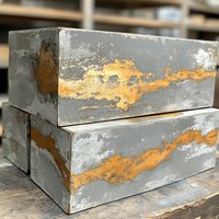 Weathered concrete blocks with natural rust stains and patina creating abstract patterns in orange and gray tones, stacked on wooden surface.