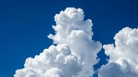 Dramatic white cumulus clouds against deep blue sky creating natural weather patterns for meteorology and atmospheric science backgrounds.