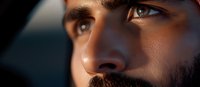 Man with dark beard and brown eyes gazing thoughtfully to the side in natural light, suitable for portraits, business profiles, and lifestyle content.