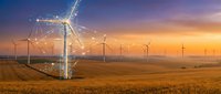 Wind turbines generating renewable energy across golden agricultural fields during dramatic sunset with construction crane installing new turbine.