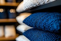 Cozy knitted sweaters in navy blue and white stacked neatly on wooden shelves, with soft selective focus creating depth and warmth in retail display.