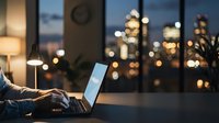 Professional working late on laptop computer in modern office with city skyline view and warm evening lighting for business productivity concepts.
