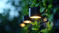 Atmospheric outdoor lighting with black pendant lamps illuminating green foliage at dusk, creating moody garden ambiance with soft bokeh effect in background.