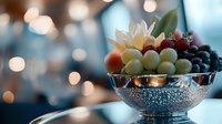 Fresh fruits in elegant silver bowl with water drops against blurred bokeh lights background, creating luxurious mood for food photography and restaurant menu design.