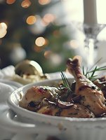 Roasted chicken drumsticks with herbs and cranberries on festive table with bokeh lights for holiday dinner celebration.