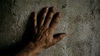 Male hand with medium skin tone pressed against rough concrete surface, showing wrinkles and texture details. Suitable for concepts of struggle, hardship, perseverance, and industrial themes.