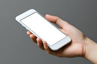 Caucasian hand holding modern white smartphone with blank screen against gray background, mockup for app and web design presentation.