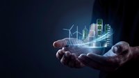 Hands holding glowing holographic smart city with wind turbines, solar panels, and modern buildings representing sustainable urban development and green energy technology.
