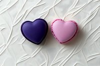 Purple and pink heart shaped macarons on textured white background. Sweet romantic dessert composition for Valentine's day celebration or wedding design.