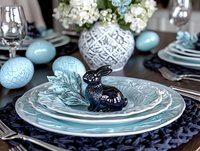 Elegant Easter table setting with blue and white porcelain plates, decorative eggs, and bunny figurine, complemented by hydrangea centerpiece and navy textiles.
