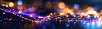 Magical glowing particles with bokeh effect in dark space, purple and orange lights creating dreamy abstract background for festive designs.