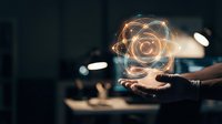 Businessman hand holding glowing digital atom symbol with light trails in modern office environment representing innovation and scientific technology.