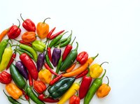 Colorful assortment of fresh hot chili peppers in various shapes and sizes on white background. Spicy vegetables for cooking and culinary applications.