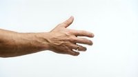 Male hand with ring reaching out on white background, fingers extended in open gesture, suitable for business and connection concepts.