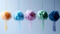 Colorful cotton candy clouds hanging on strings against light background, soft fluffy texture in pastel orange, blue, pink, mint and navy shades create dreamy arrangement.