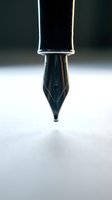 Macro close-up of a fountain pen nib with reflective metal barrel against neutral background, suitable for writing, stationery, and office design projects.