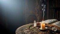 Mystical altar setup with burning candle, ancient books, herbs and occult symbols on wooden table creating atmospheric spiritual scene for rituals.