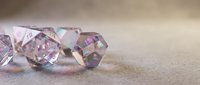 Sparkling transparent crystals with rainbow reflections scattered on soft beige surface creating elegant luxury background for jewelry design and decoration.
