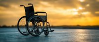 Wheelchair positioned on beach sand at golden hour sunset, symbolizing accessibility, inclusion, and outdoor recreation for people with mobility challenges.