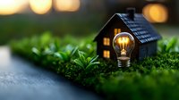 Glowing light bulb and miniature house on green moss with bokeh background creates magical atmosphere for eco-friendly home and energy concepts.